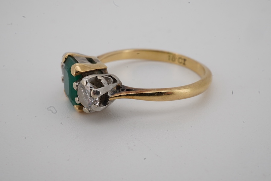 An 18ct, emerald and diamond set three stone ring, size M, gross weight 3.7 grams, (emerald cracked).